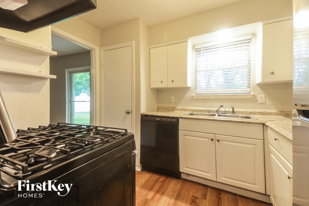 A kitchen with a black stove top oven and white cabinets.