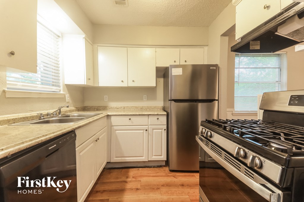 A kitchen with a stove, sink, and cabinets.