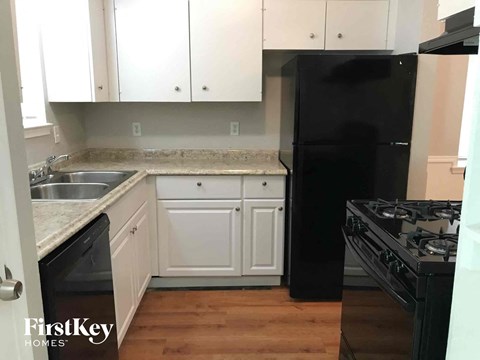 A kitchen with a black fridge and stove top oven.