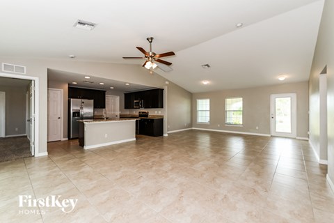 A spacious kitchen and living room with a ceiling fan and lighting fixtures.