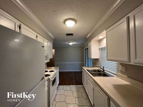 A kitchen with white cabinets and a white refrigerator.