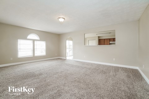 A spacious room with a carpeted floor and a large window.