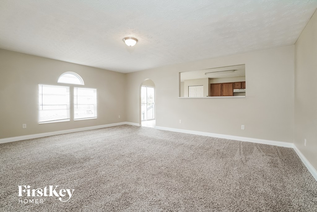 A spacious room with a carpeted floor and a large window.