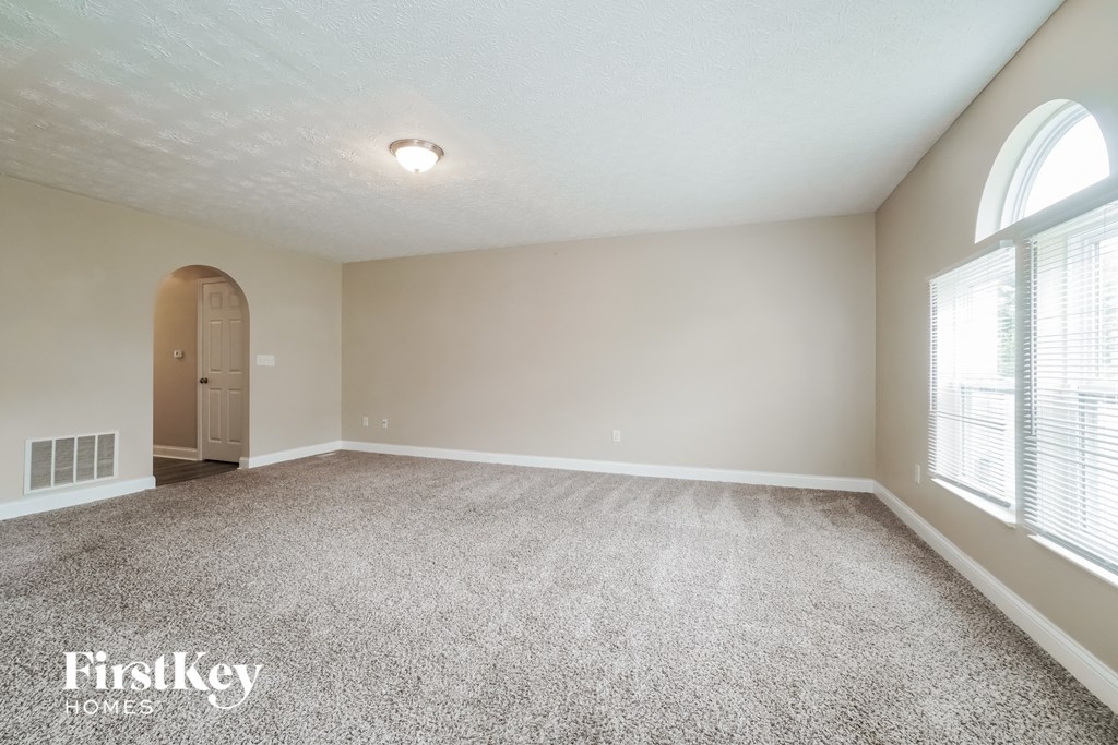 A spacious room with a carpeted floor and a door on the left side.