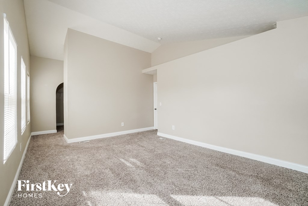 A spacious room with a carpeted floor and a doorway leading to another room.