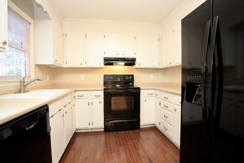 A black refrigerator is on the right side of a kitchen.