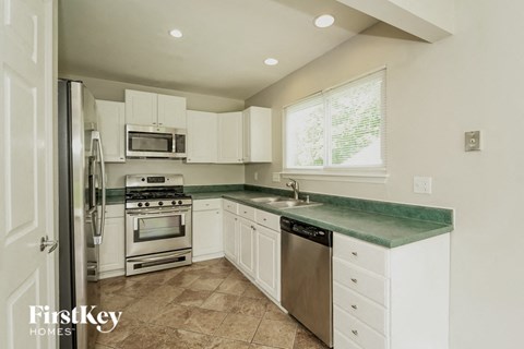 A kitchen with white cabinets and a green counter top.