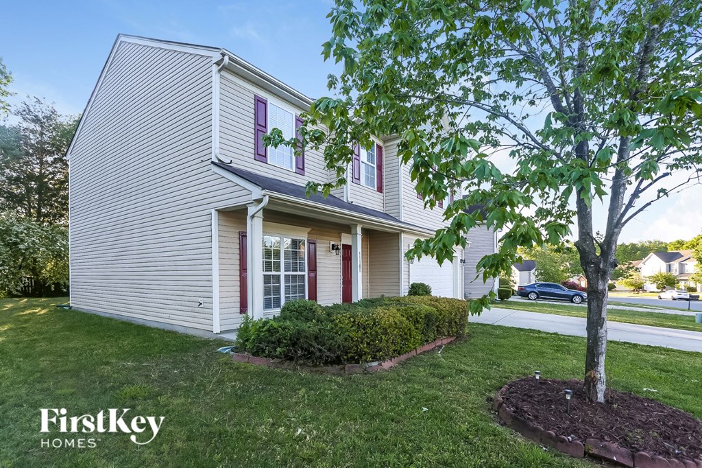 a white house with red shutters and a tree in the yard