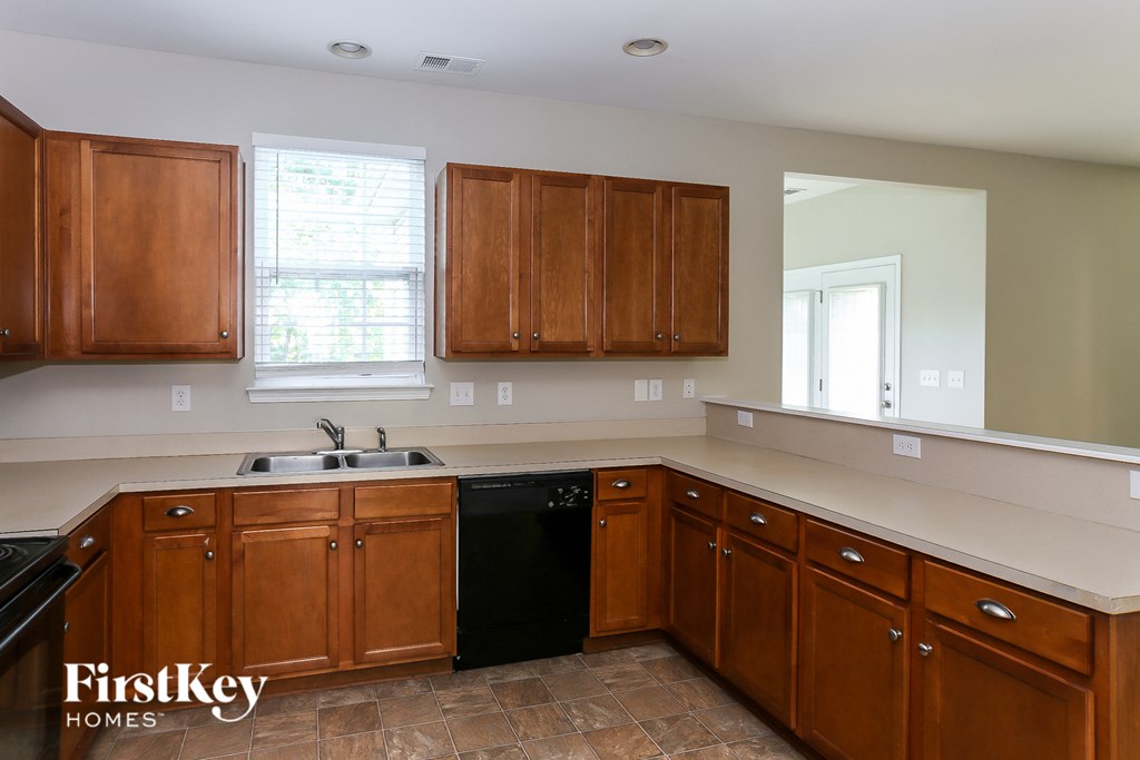 a kitchen with wooden cabinets and a black dishwasher