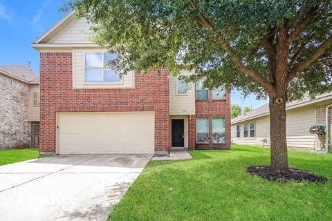 A red brick house with a tree in front.