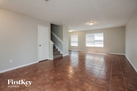 A room with a brown floor and a staircase leading to the second floor.