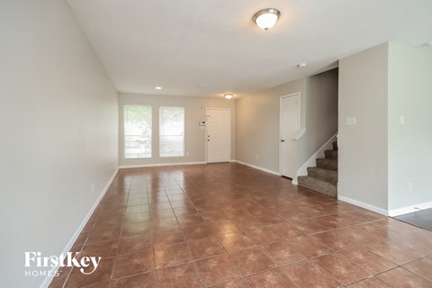 A spacious room with a staircase and a brown floor.