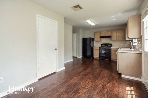 A kitchen with wooden floors and a black fridge.