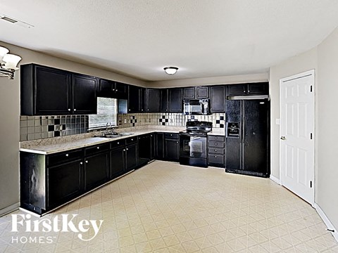 A kitchen with black cabinets and a white door.