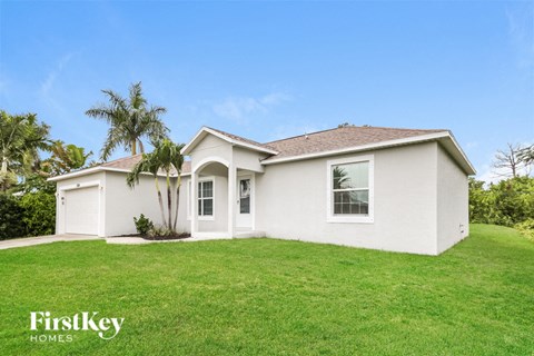 a white house with a green lawn and a palm tree
