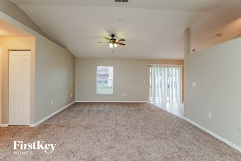 a spacious living room with carpet and a ceiling fan