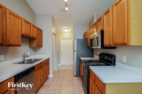 a kitchen with wood cabinets and black appliances and white counter tops