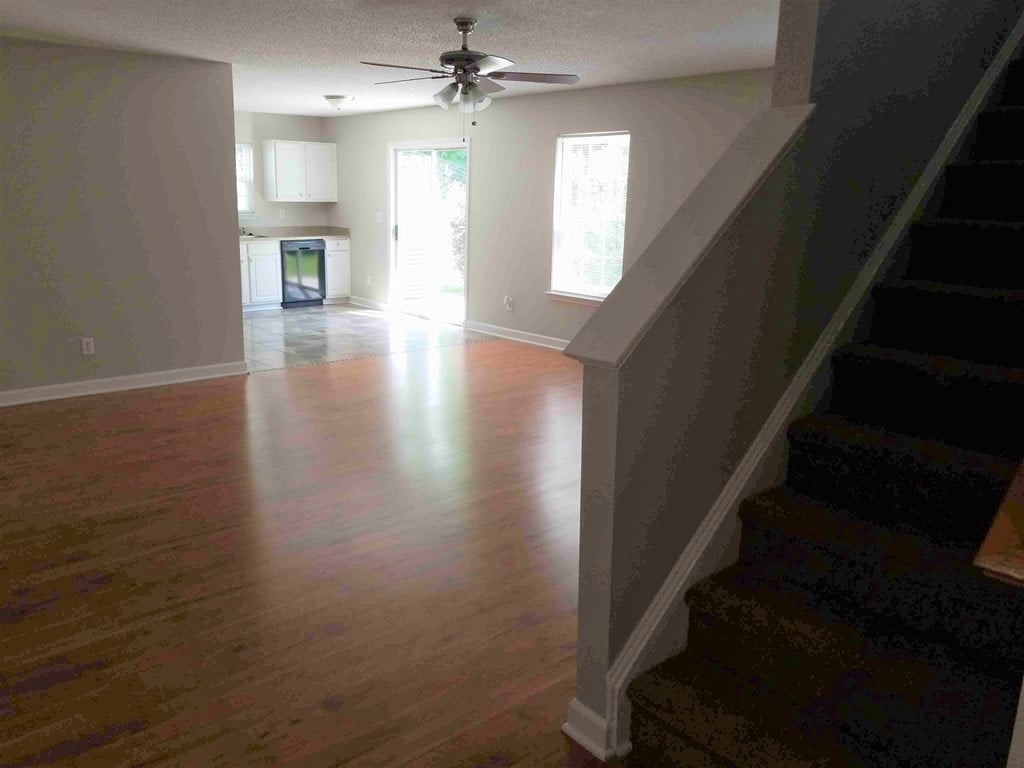 an empty living room with a ceiling fan and a hard wood floor
