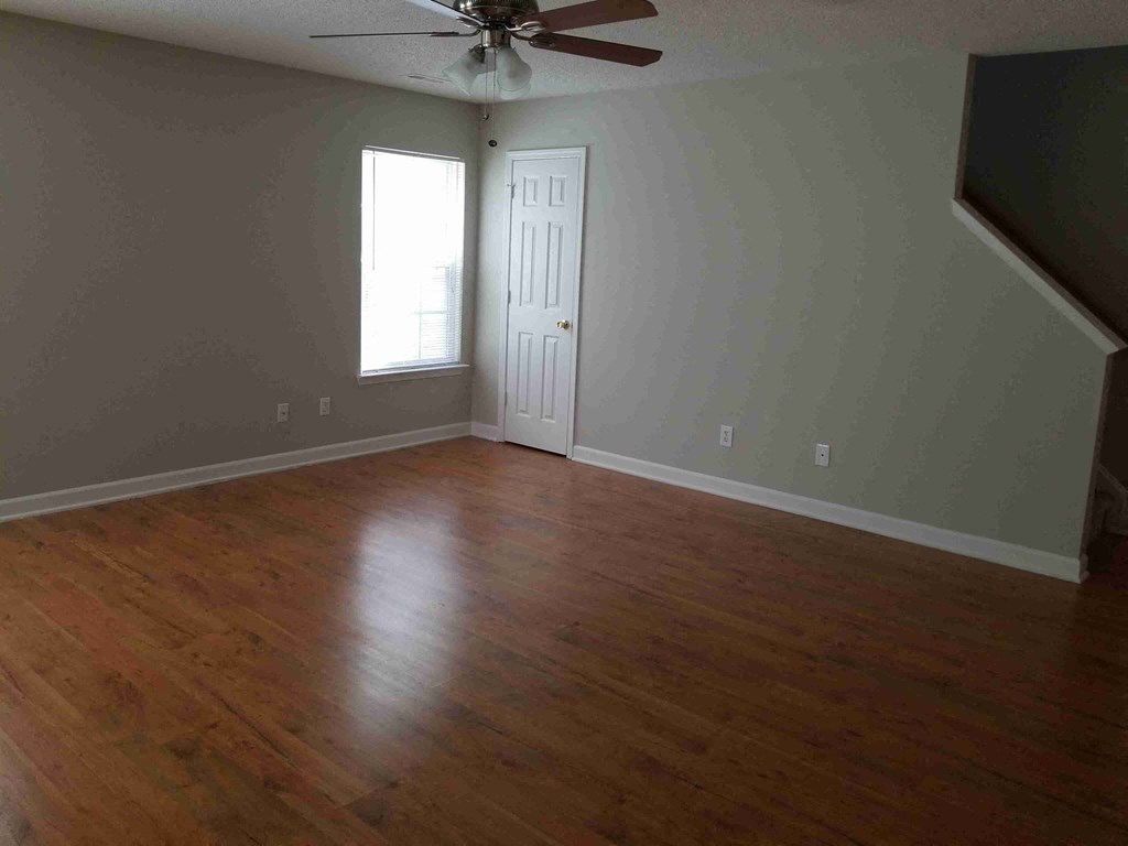 an empty living room with wooden floors and a ceiling fan