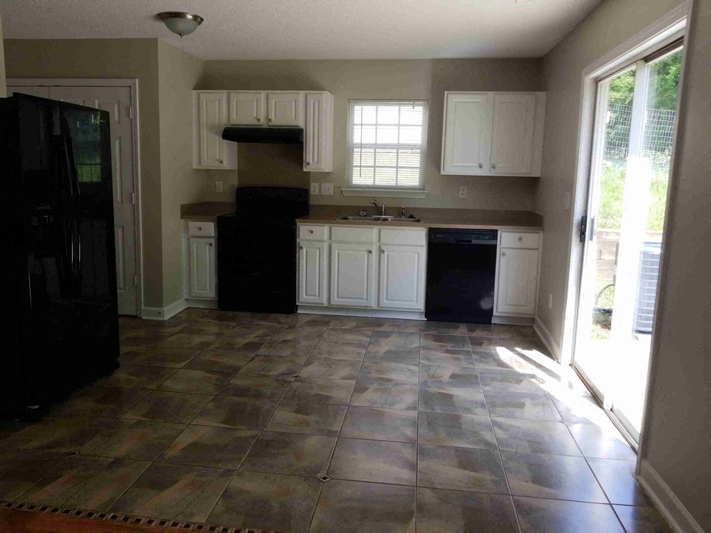 an empty kitchen with white cabinets and tile flooring