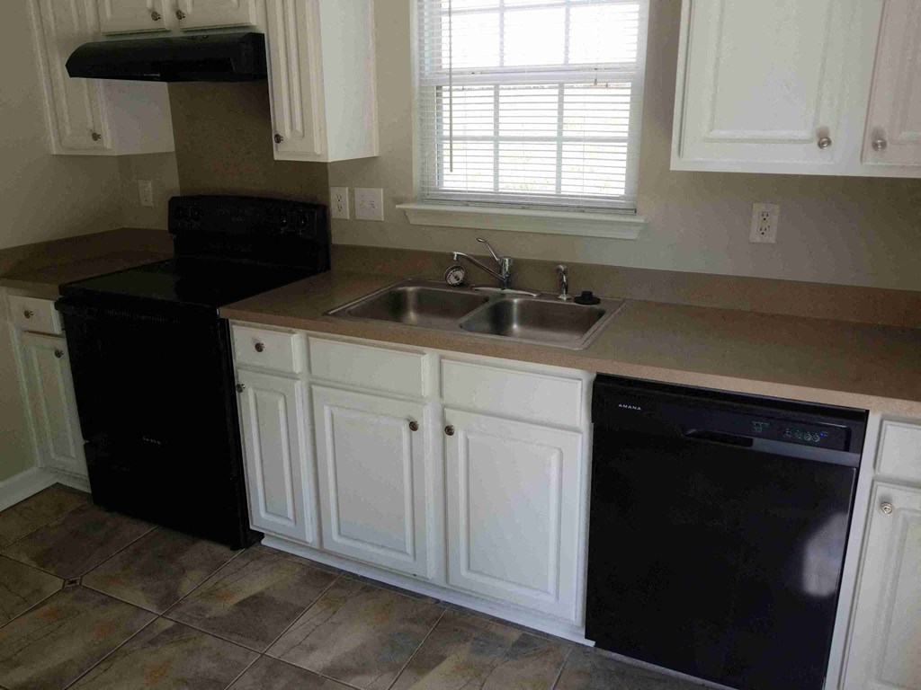 a kitchen with white cabinets and a black dishwasher and sink
