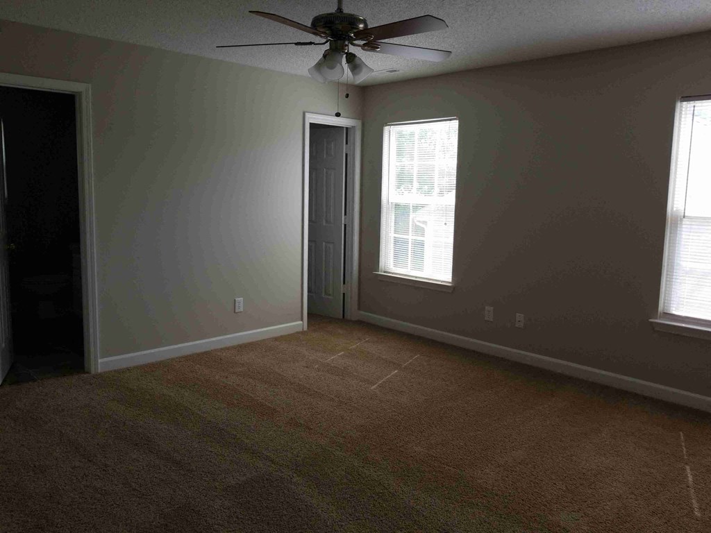 an empty living room with a ceiling fan