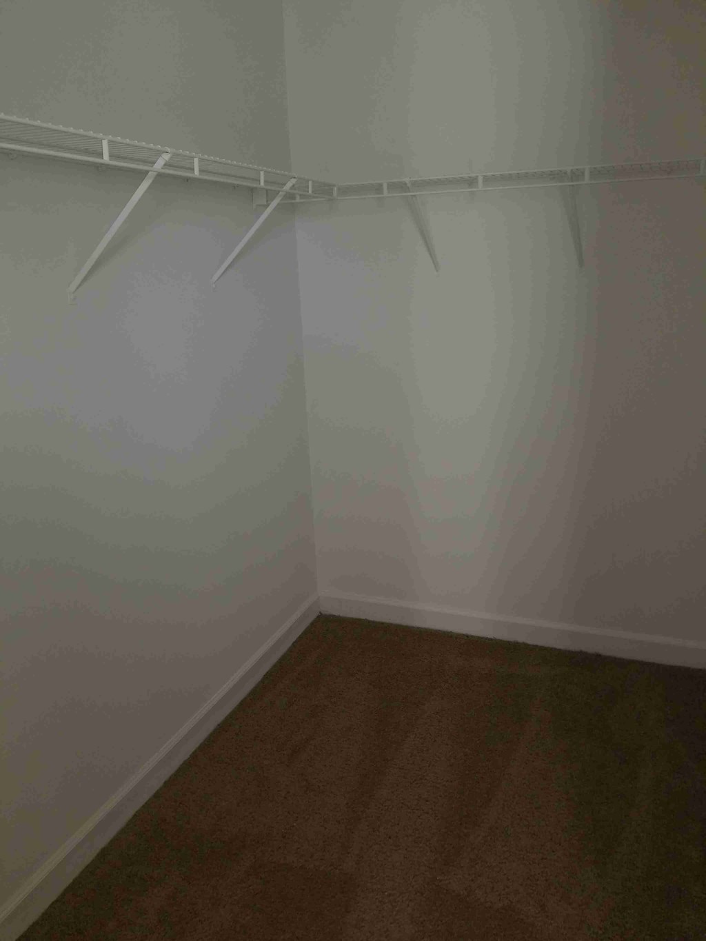 a room with a wooden floor and a white wall with white hangers