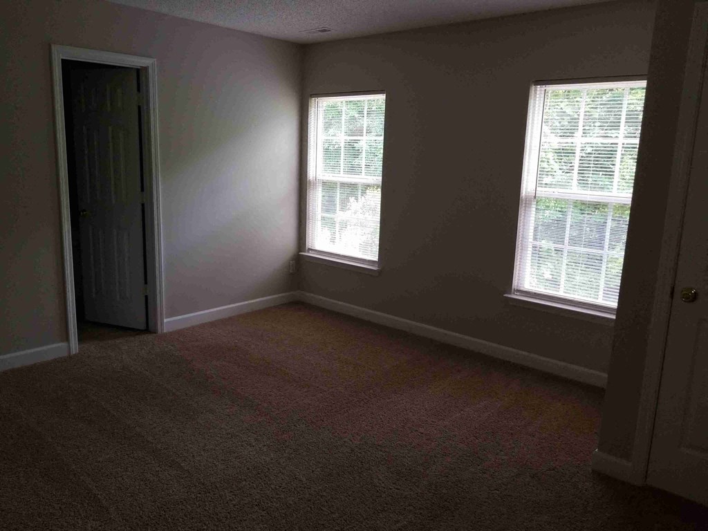 an empty room with two windows and a door