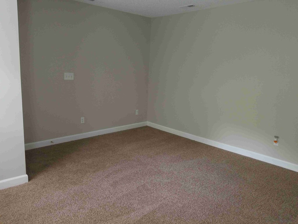 an empty room with carpet and a white wall