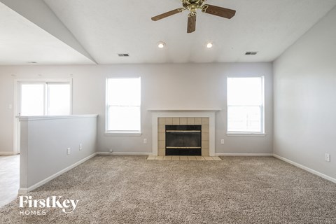 A spacious living room with a fireplace and a ceiling fan.