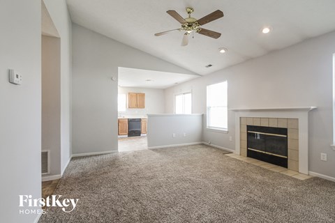 A spacious living room with a fireplace and a ceiling fan.