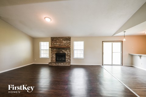 the living room of a house with a fireplace and wooden floors