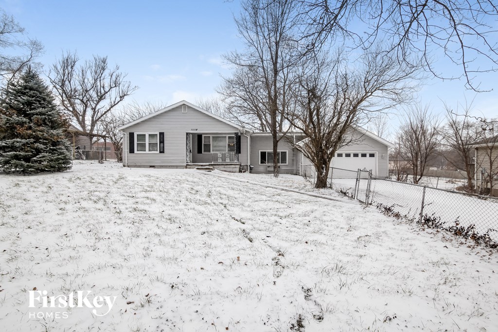 A house with a snowy yard in front of it.