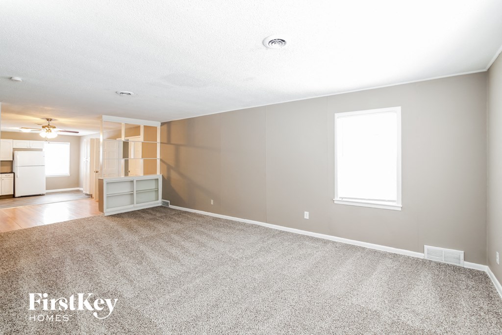 A spacious room with a carpeted floor and a window.