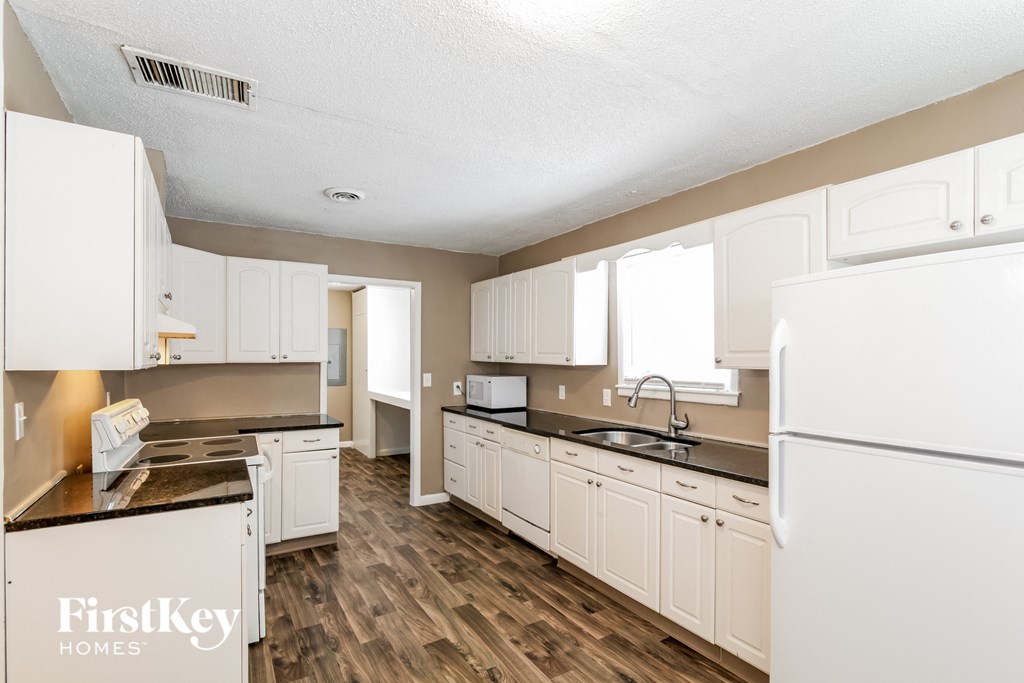 A kitchen with white appliances and cabinets.