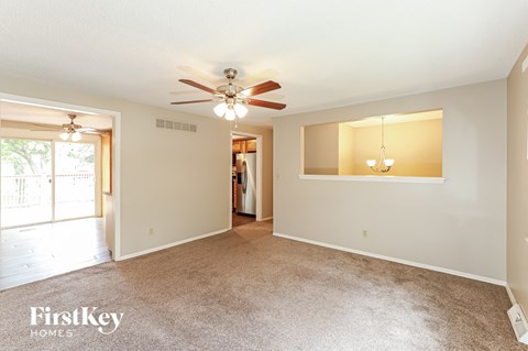 A spacious room with a ceiling fan and a large window.