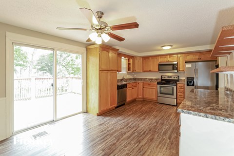 A kitchen with wooden cabinets and a ceiling fan.