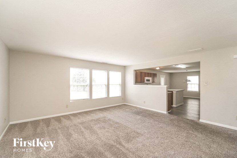A spacious empty room with a carpeted floor and a large window.