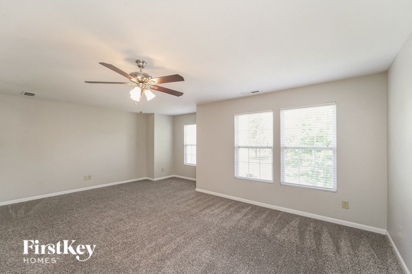 A spacious room with a ceiling fan and carpeted floor.