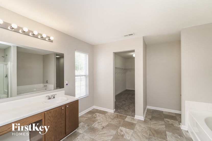 A bathroom with a sink, mirror, and tiled floor.