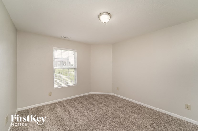 A room with a carpeted floor and a window with blinds.