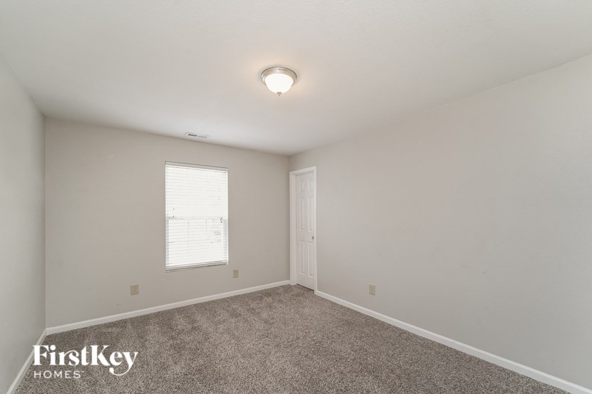 A room with a carpeted floor and a window with blinds.
