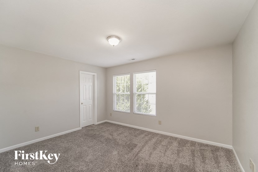 A room with a carpeted floor and a window with blinds.