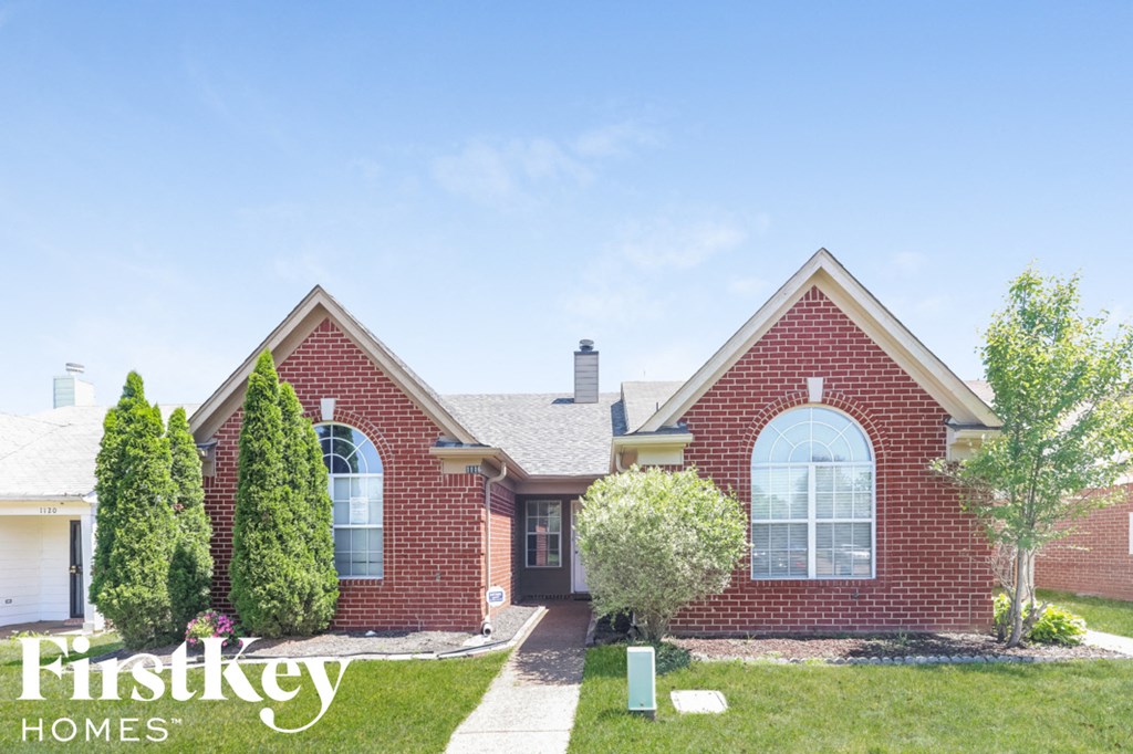 A brick house with a white door and windows is for sale.