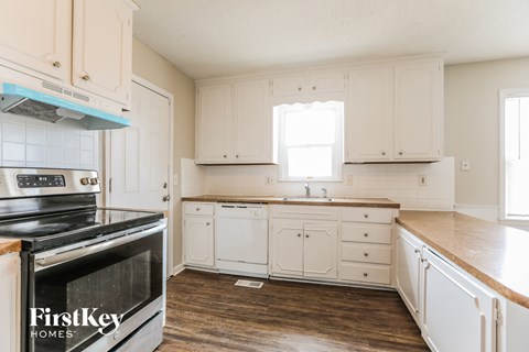 A kitchen with white cabinets and a black stove top oven.