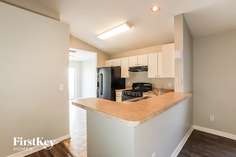 a kitchen with white cabinets and a counter top and a black refrigerator