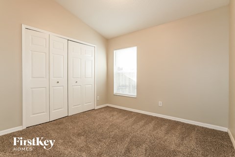 a bedroom with carpet and two closets and a window