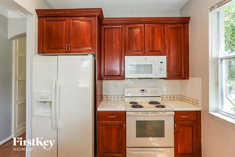 a kitchen with wooden cabinets and white appliances and a refrigerator