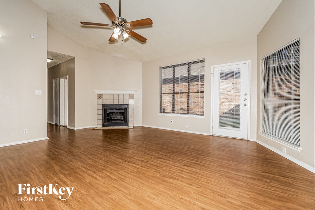 A spacious living room with a fireplace and a ceiling fan.