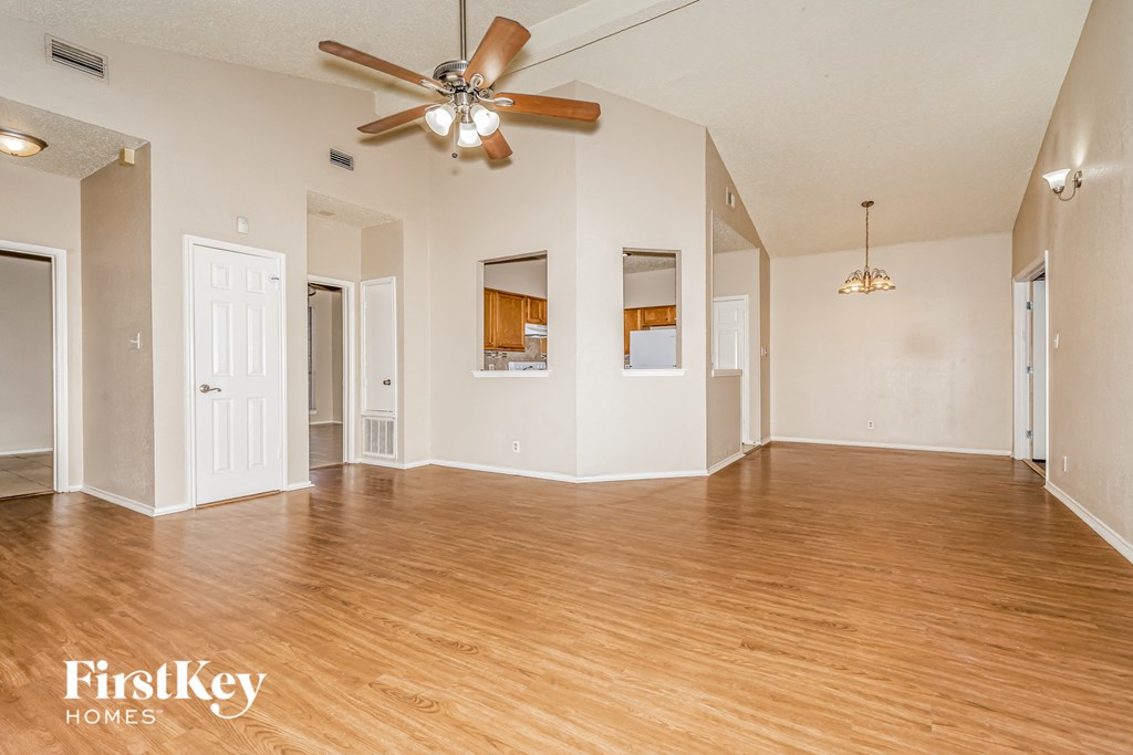 A spacious room with wooden floors and a ceiling fan.